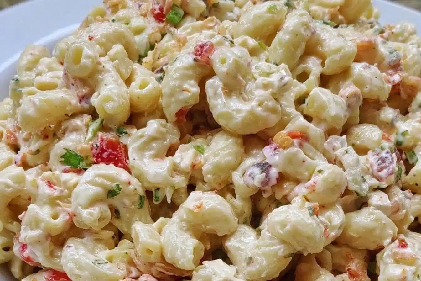 Delicious creamy macaroni salad served in a bowl, garnished with herbs.